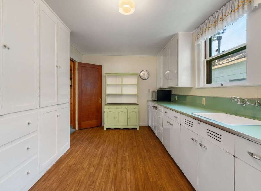 Step into this charming kitchen, featuring classic white cabinetry and a unique green countertop.