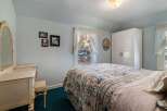 Step into this charming bedroom, featuring a cozy bed adorned with a floral quilt and a serene ambiance.