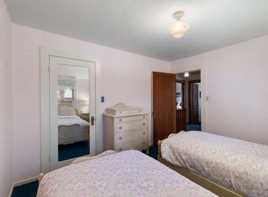 This charming bedroom features two twin beds with floral bedding, perfect for guests or family.