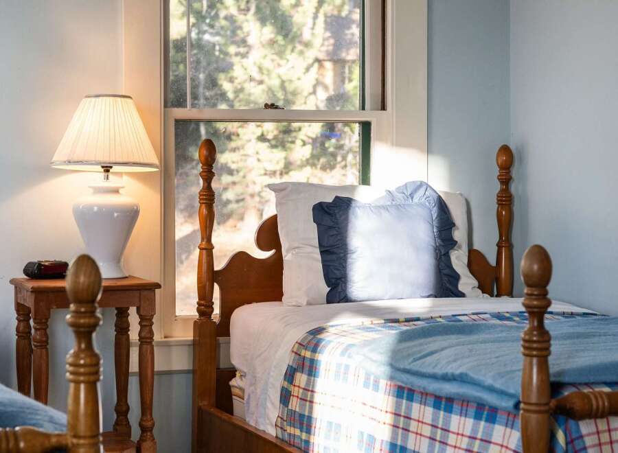 This charming bedroom features a cozy bed with a plaid blanket and a decorative pillow, perfect for a relaxing retreat.