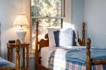 This charming bedroom features a cozy bed with a plaid blanket and a decorative pillow, perfect for a relaxing retreat.