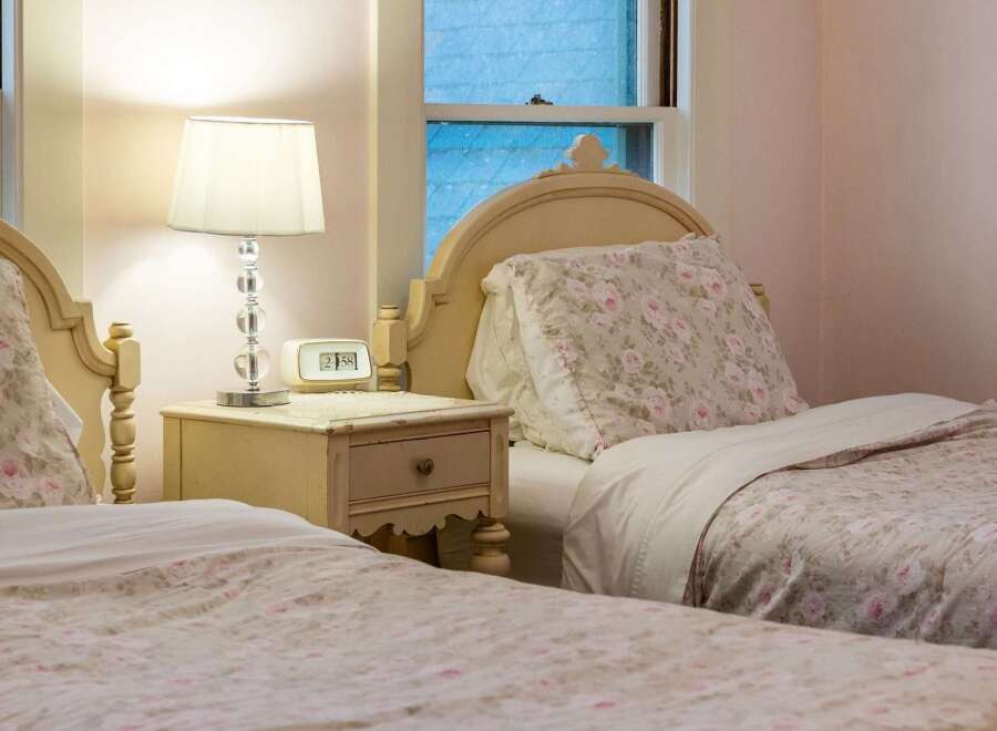 This charming bedroom features two twin beds with floral bedding, creating a cozy and inviting atmosphere.