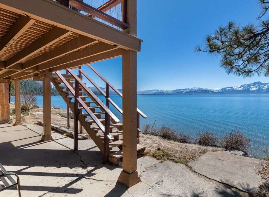Enjoy stunning lake views from this charming property! This home features a beautiful wooden staircase leading to a deck, perfect for relaxing and taking in the scenery.