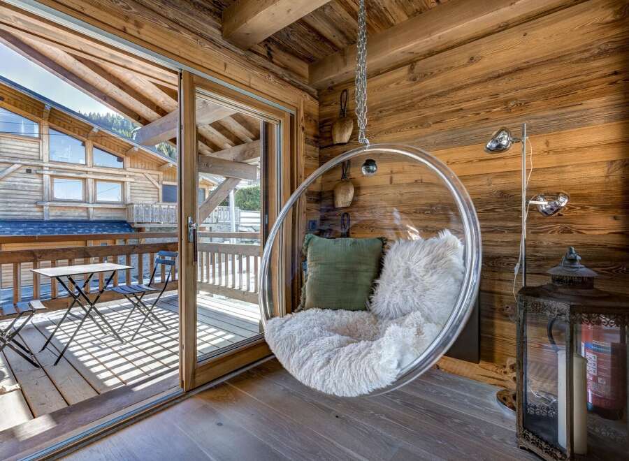 Experience ultimate relaxation in this stunning chalet, featuring a unique hanging chair and a cozy, inviting atmosphere.