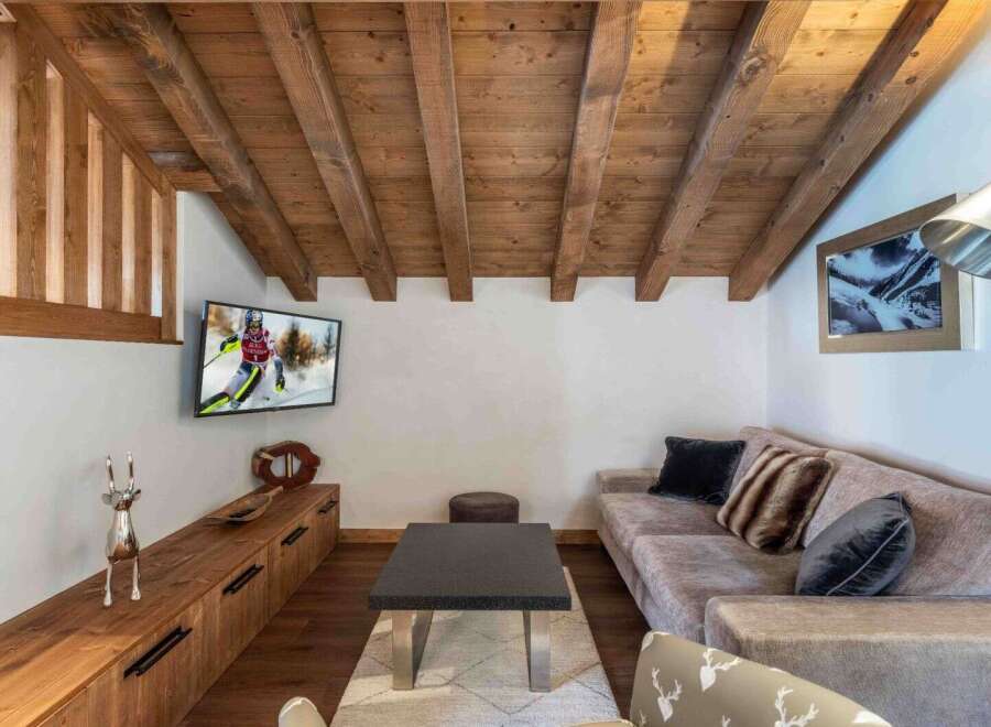 This cozy living space features a rustic wooden ceiling and a comfortable sofa, perfect for relaxing after a day on the slopes.