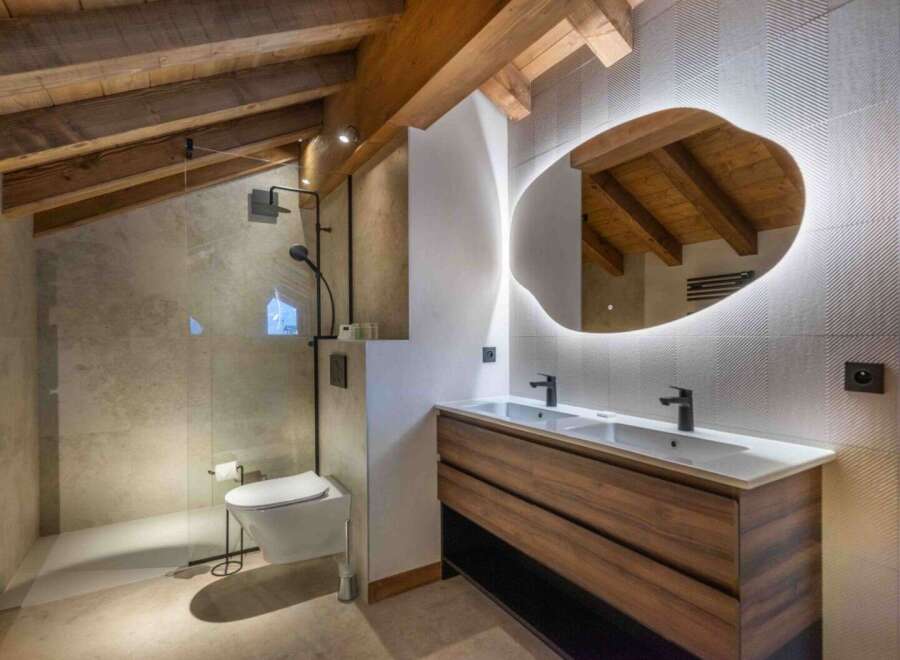 This stunning bathroom boasts a unique design with exposed wooden beams and a modern, irregular-shaped mirror.