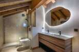 This stunning bathroom boasts a unique design with exposed wooden beams and a modern, irregular-shaped mirror.
