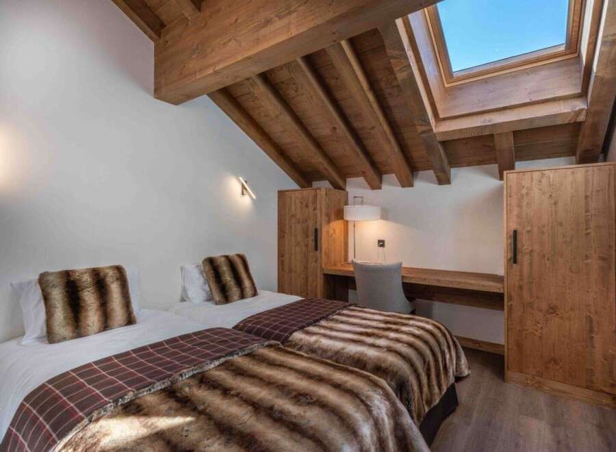 This cozy bedroom features two twin beds with luxurious faux fur throws and pillows, perfect for a comfortable stay.