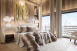 Experience luxury living in this stunning bedroom, featuring a cozy bed adorned with plush bedding and a faux fur throw.