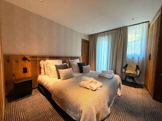 Experience ultimate comfort in this beautifully appointed bedroom, featuring a plush king-size bed adorned with soft linens and decorative pillows.