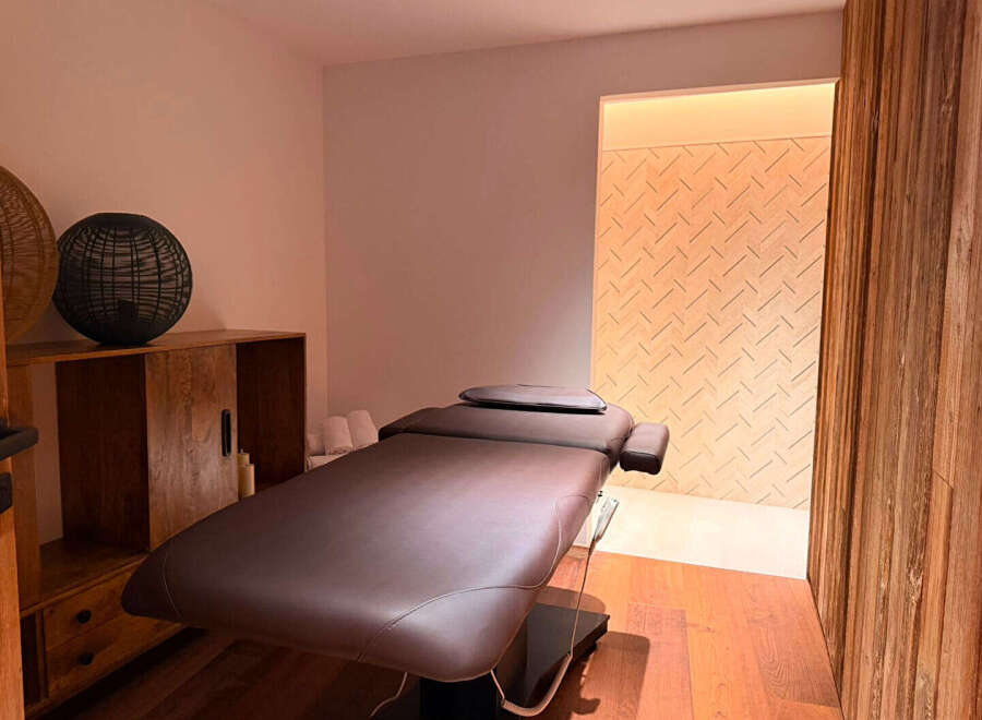 Experience ultimate relaxation in this serene spa room, featuring a comfortable massage table and elegant wooden accents.