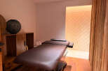 Experience ultimate relaxation in this serene spa room, featuring a comfortable massage table and elegant wooden accents.