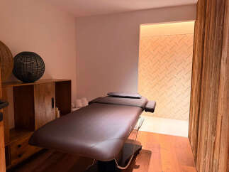 Experience ultimate relaxation in this serene spa room, featuring a comfortable massage table and elegant wooden accents.