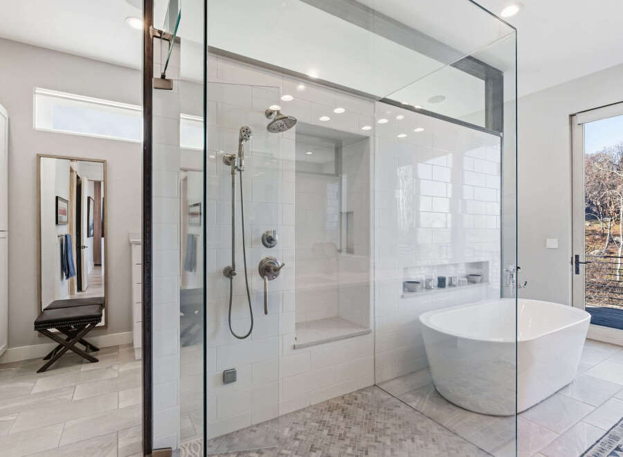Step into luxury with this stunning bathroom featuring a spacious glass-enclosed shower and a modern soaking tub.