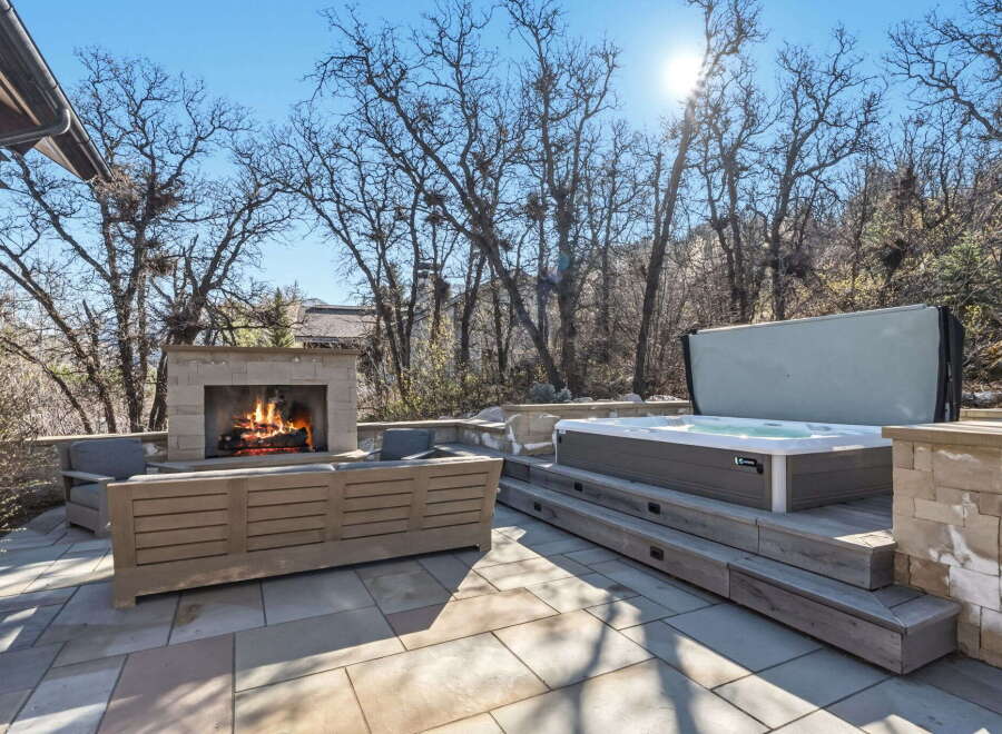 Enjoy luxurious outdoor living with this stunning property featuring a cozy fireplace and a relaxing hot tub.