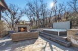 Enjoy luxurious outdoor living with this stunning property featuring a cozy fireplace and a relaxing hot tub.