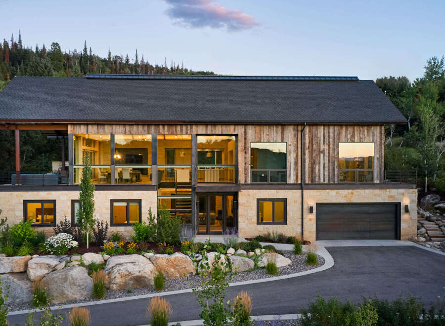 This stunning modern home boasts a striking exterior with a combination of wood and stone elements, creating a warm and inviting aesthetic.