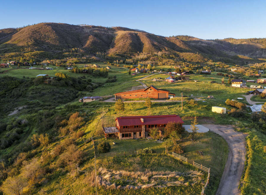 Experience serene mountain living in this stunning property featuring a spacious main house with a stone foundation and a large wooden barn perfect for storage or equestrian use.