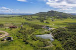 Discover this expansive rural property featuring a serene pond, multiple outbuildings, and a charming red-roofed home.