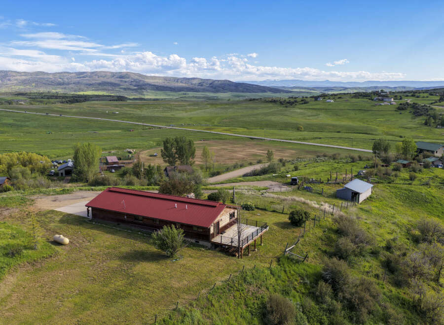 Discover this expansive property featuring a charming home with a striking red metal roof and a spacious deck, perfect for enjoying the scenic mountain views.