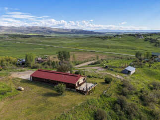 Discover this expansive property featuring a charming home with a striking red metal roof and a spacious deck, perfect for enjoying the scenic mountain views.