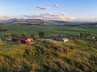 Experience serene mountain living with this stunning property, featuring a charming wooden home with a spacious deck perfect for enjoying the breathtaking sunset views.