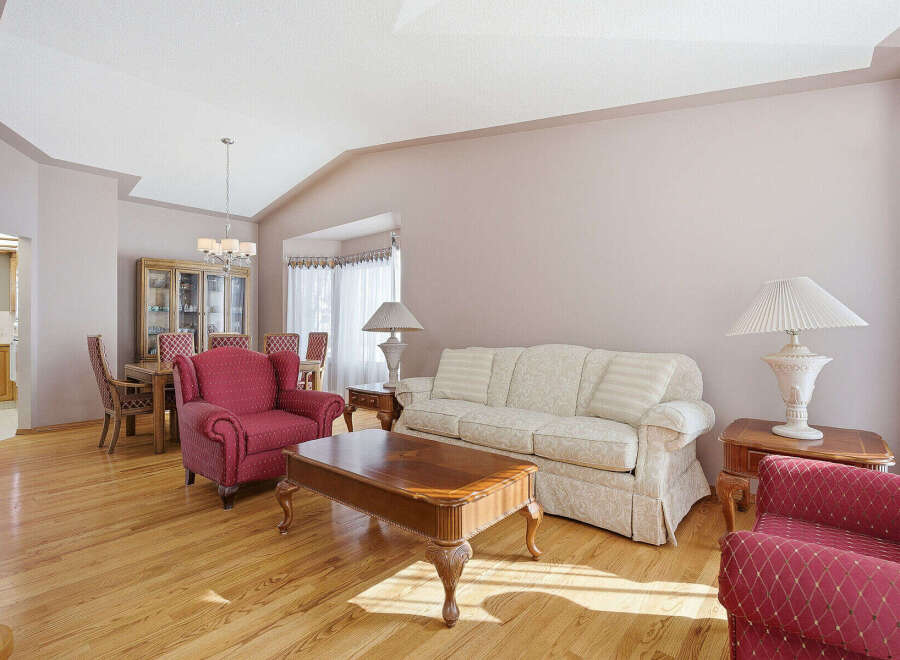 This elegant living room features hardwood floors, a comfortable sofa, and two armchairs, creating a warm and inviting atmosphere.