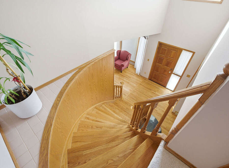 This stunning property features a grand, curved staircase with beautiful wooden steps and a matching railing, creating an elegant focal point.