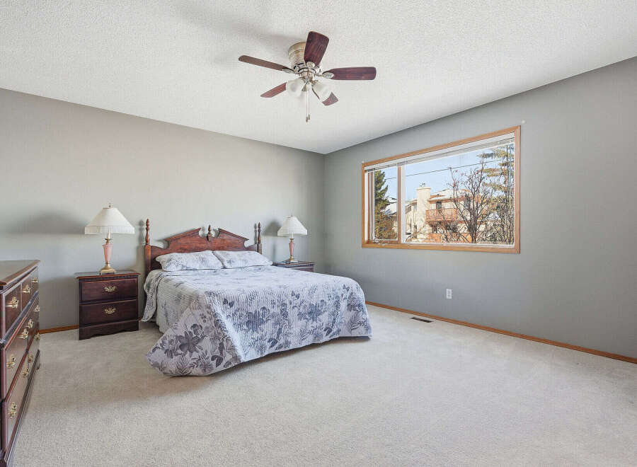 This spacious bedroom offers a serene retreat with its neutral color palette and ample natural light.