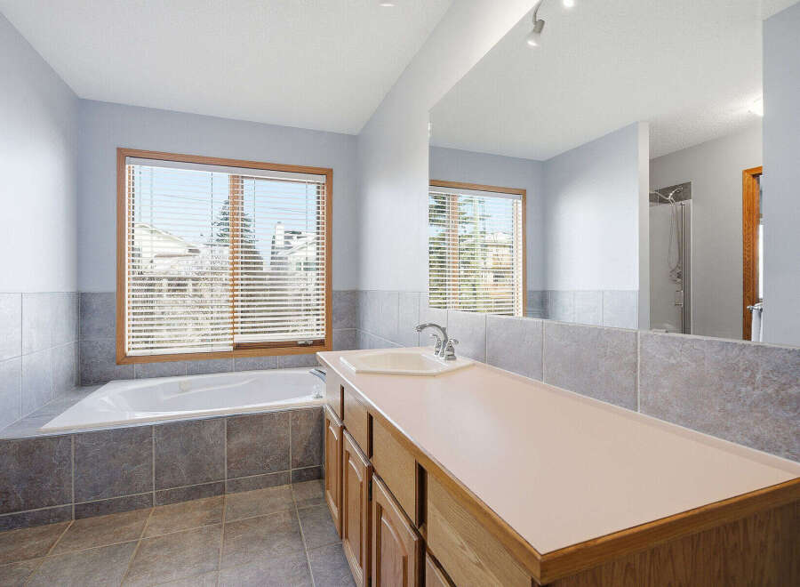 Step into this bright and airy bathroom, featuring a luxurious soaking tub and a spacious vanity.