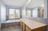 Step into this bright and airy bathroom, featuring a luxurious soaking tub and a spacious vanity.