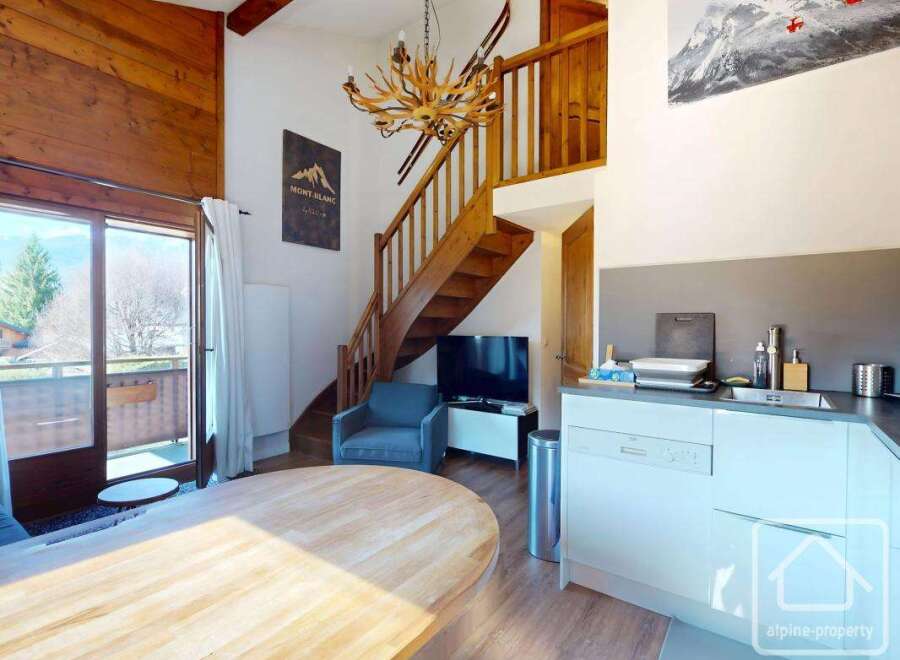 Discover this charming property featuring a cozy living space with a wooden staircase and a modern kitchen.