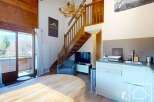 Discover this charming property featuring a cozy living space with a wooden staircase and a modern kitchen.