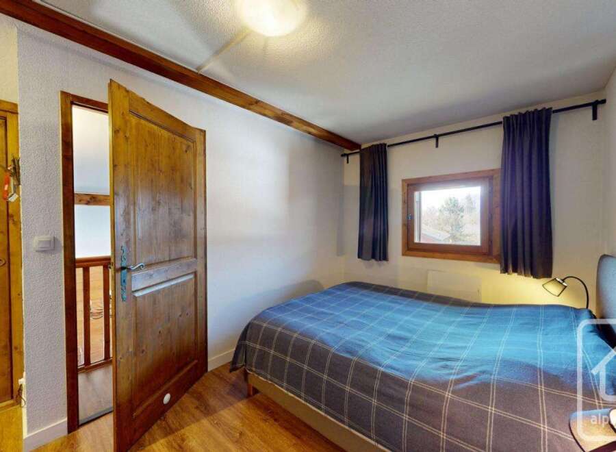 Discover this charming bedroom featuring a cozy bed with a stylish blue plaid comforter, perfect for a relaxing retreat.