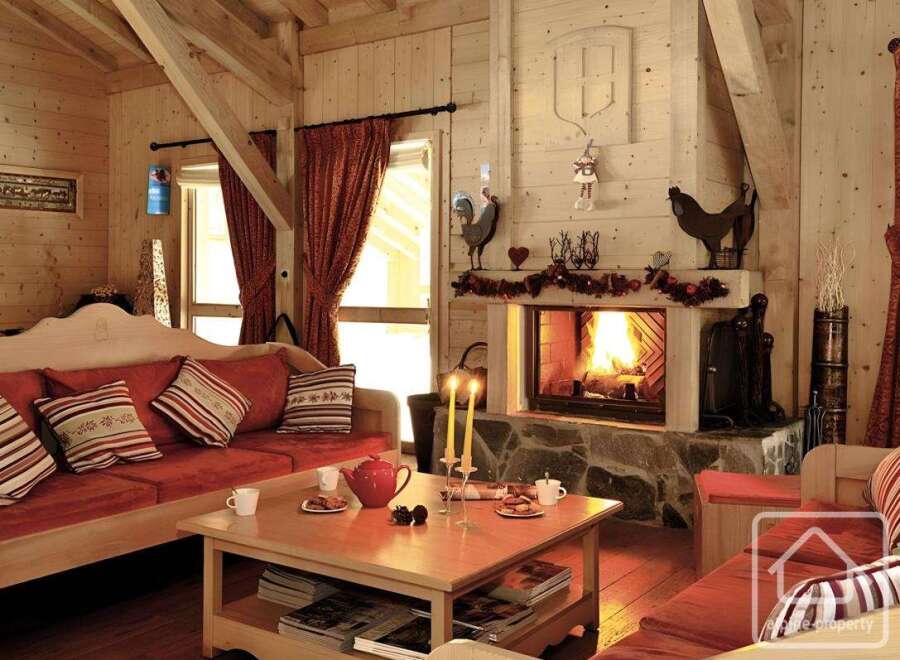 Experience the warmth of this cozy living room, featuring a rustic fireplace and inviting red sofa.