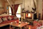 Experience the warmth of this cozy living room, featuring a rustic fireplace and inviting red sofa.