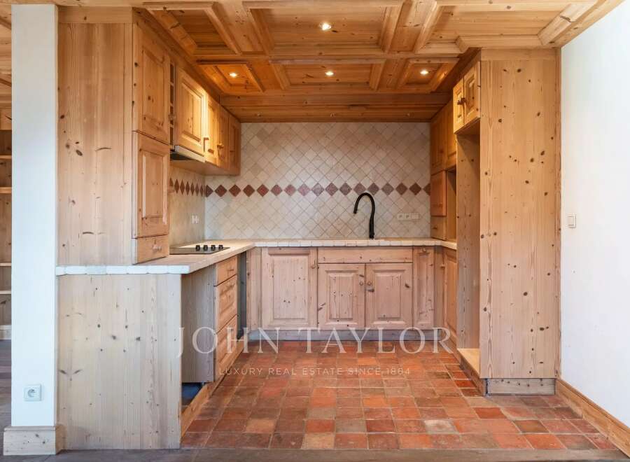This stunning kitchen showcases a rustic charm with its wooden cabinetry and terracotta tile flooring.