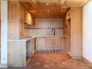 This stunning kitchen showcases a rustic charm with its wooden cabinetry and terracotta tile flooring.