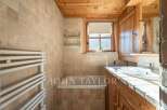 This charming bathroom features a warm, inviting ambiance with its wooden accents and natural stone tiles.