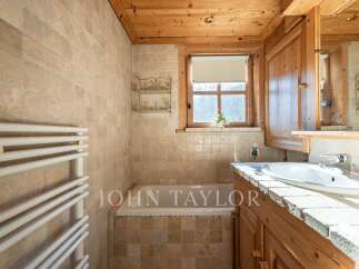 This charming bathroom features a warm, inviting ambiance with its wooden accents and natural stone tiles.