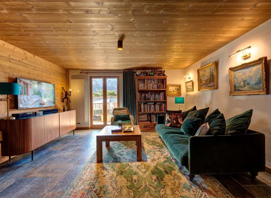 Step into luxury with this stunning living room, featuring a cozy green velvet sofa and a beautiful wooden ceiling.
