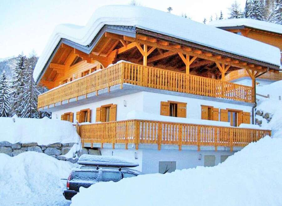 This stunning chalet-style home is nestled in a snowy landscape, offering a cozy retreat.