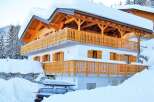 This stunning chalet-style home is nestled in a snowy landscape, offering a cozy retreat.
