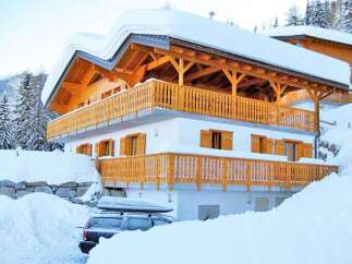 This stunning chalet-style home is nestled in a snowy landscape, offering a cozy retreat.