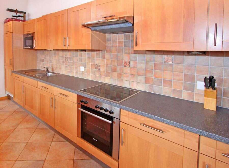 This kitchen features beautiful wooden cabinets and a modern cooktop, perfect for preparing delicious meals.