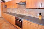 This kitchen features beautiful wooden cabinets and a modern cooktop, perfect for preparing delicious meals.