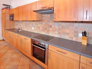 This kitchen features beautiful wooden cabinets and a modern cooktop, perfect for preparing delicious meals.