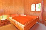 This cozy bedroom features warm wooden paneling and a comfortable bed with an inviting orange comforter.