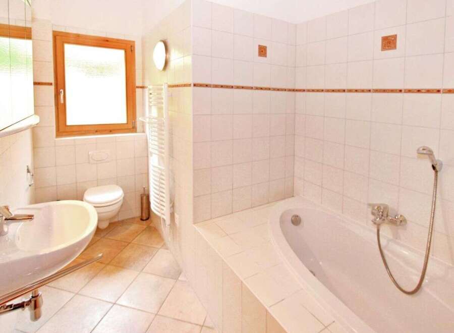 This inviting bathroom features a bright, airy design with pristine white tiles and a relaxing bathtub.