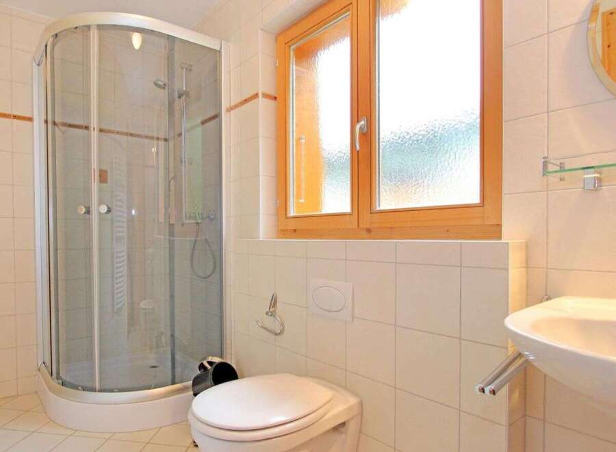 This bathroom features a modern shower with glass doors, providing a sleek and functional space.